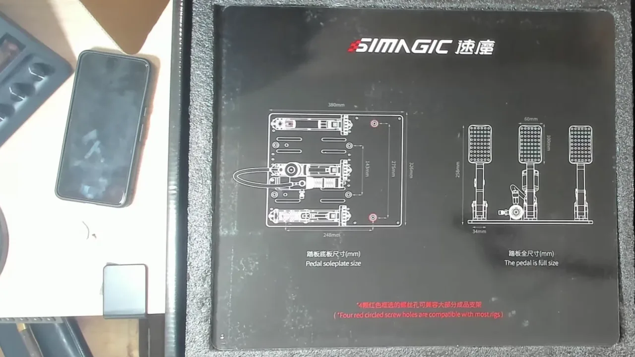 Simagic imprime les cotes dans la boîte : 380 × 326 mm, et quatre trous entourés de rouge, compatibles « avec la plupart des châssis ».