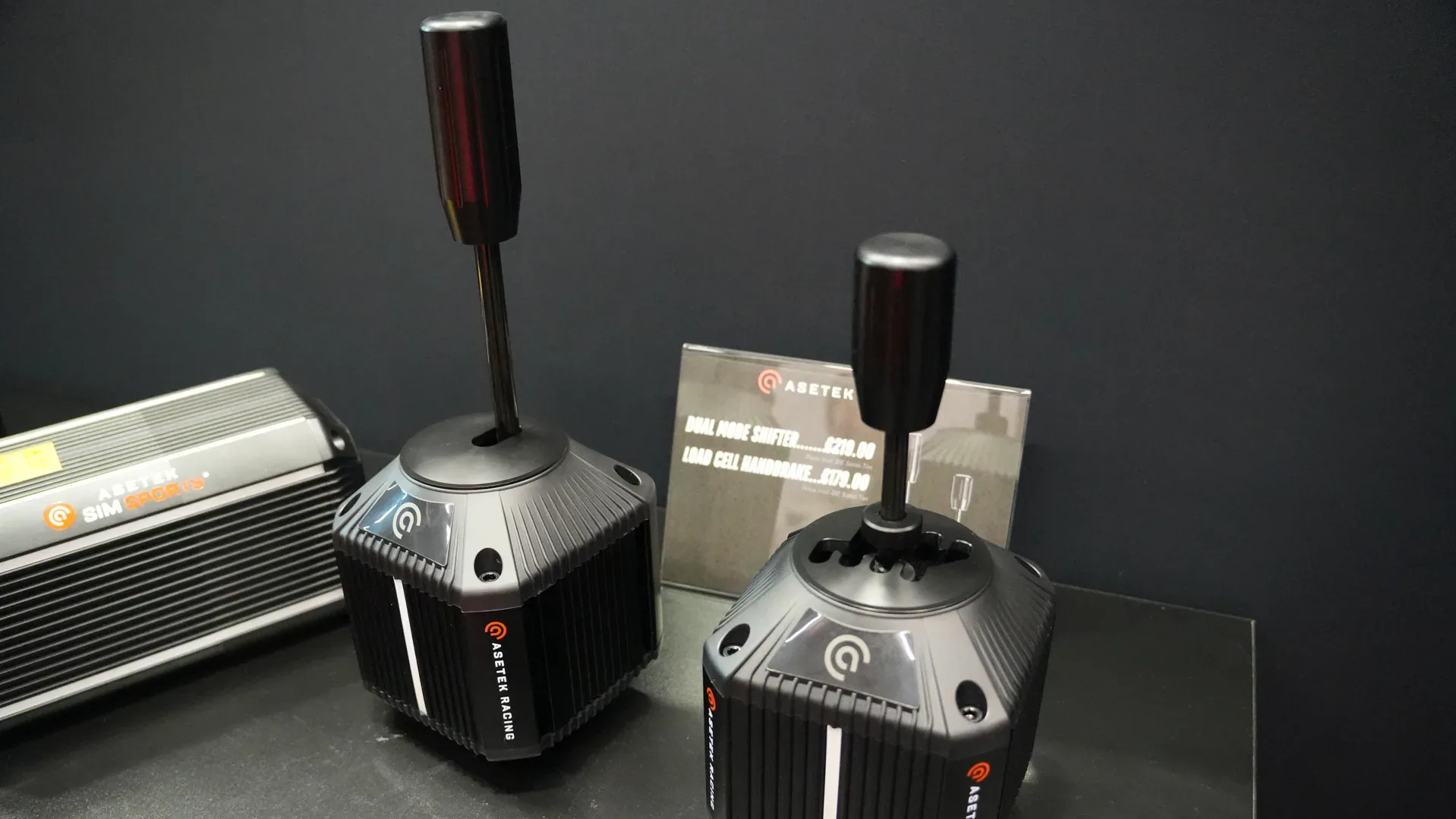 Le Dual Mode Shifter et le frein à main load cell d'Asetek, sortis le 6 octobre. Le panneau du stand les affiche à 219 € et 179 €.
