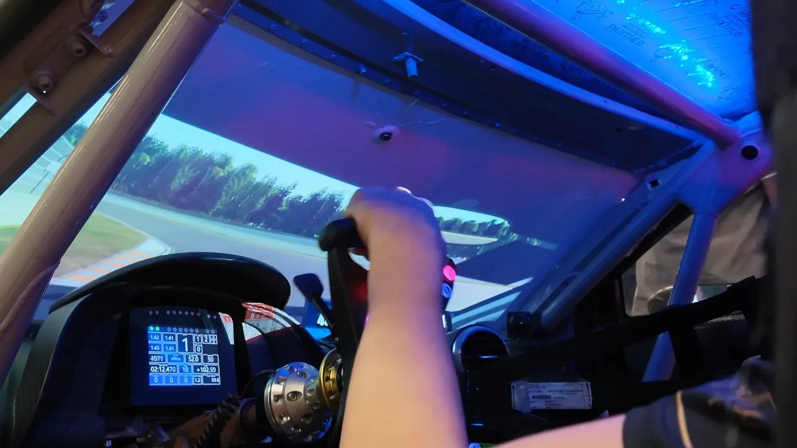 À bord de la vraie voiture du stand Conspit, une base au volant et un écran incurvé à la place du pare-brise.