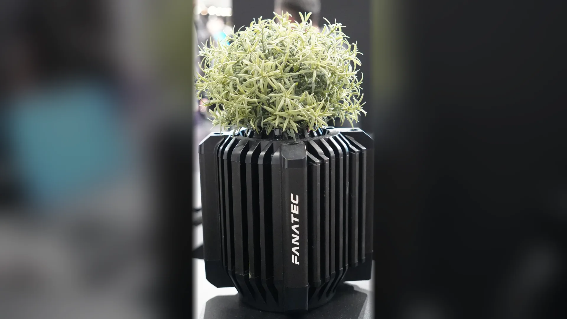 Clin d'œil du stand Fanatec : le carter d'une base direct drive transformé en pot de plante.
