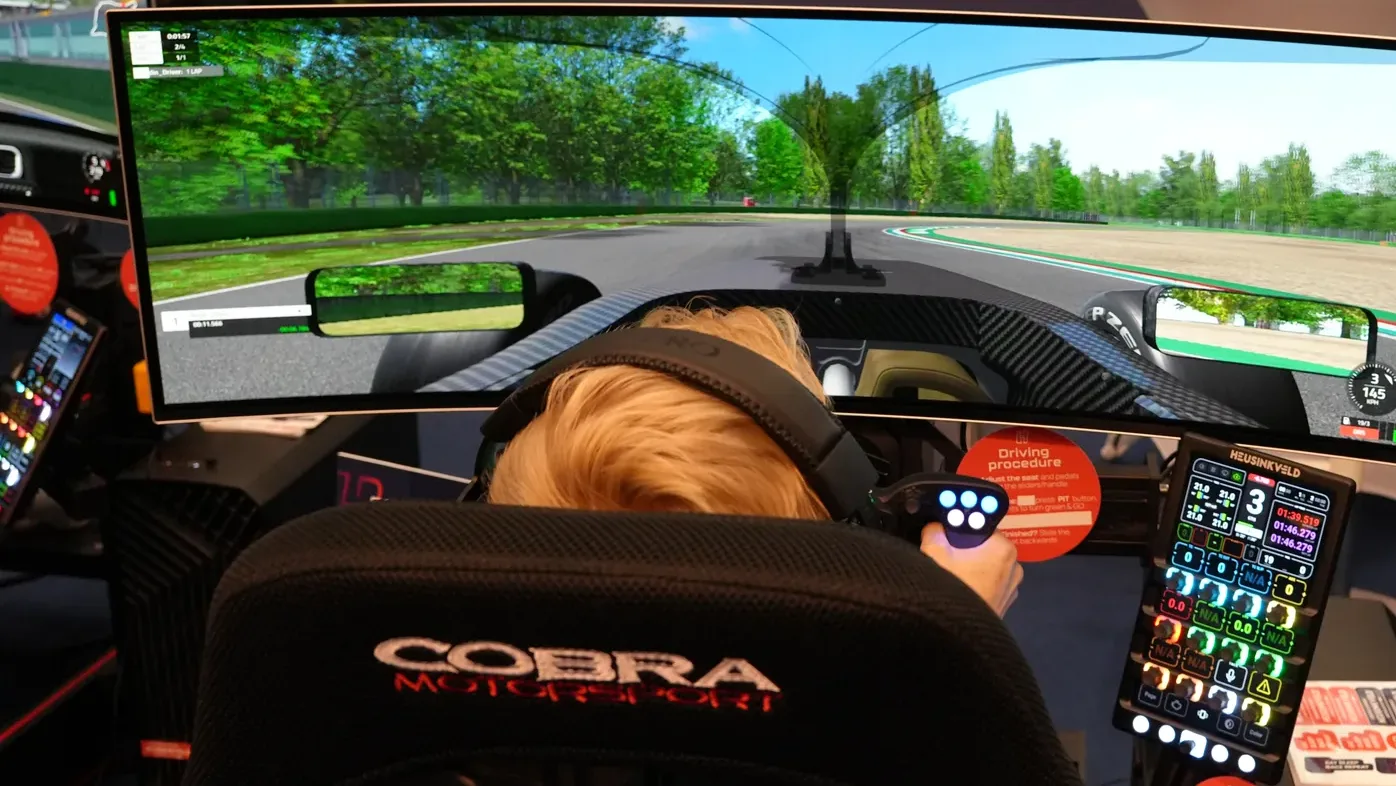 Un pilote en roulage sur le stand Heusinkveld, le DisplayDash à côté du volant. On en reparle plus bas.