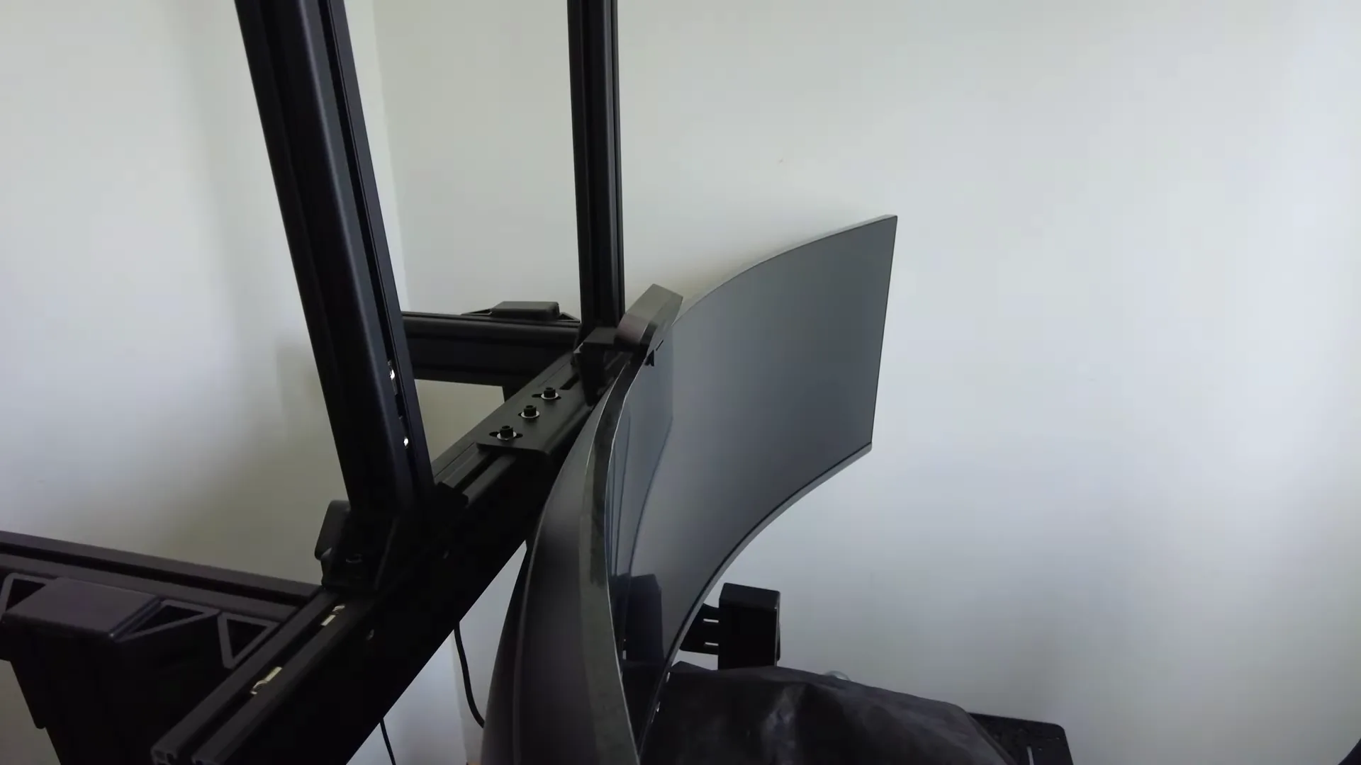 Les deux montants, vissés sur la barre qui porte l'ultrawide, avec deux équerres au pied de chacun. Tout le reste du support repose sur eux.