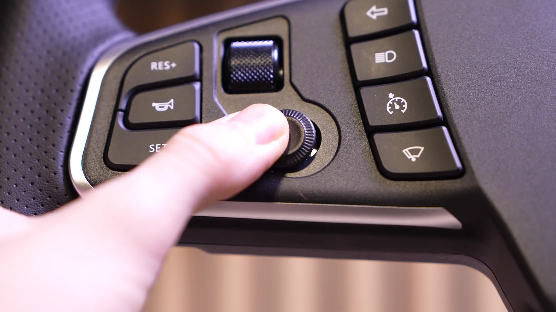 Gros plan sur les boutons du volant : cruise control, essuie-glaces et molette