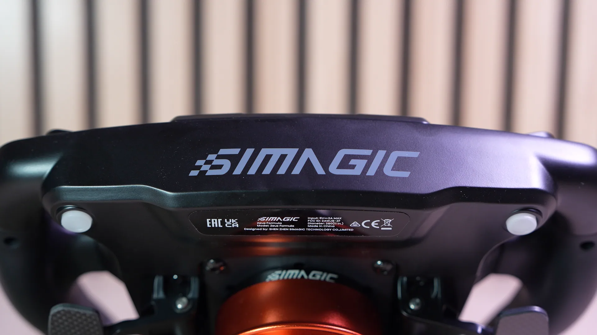Le dos du volant, logo Simagic gravé, avec le quick release orange visible en bas
