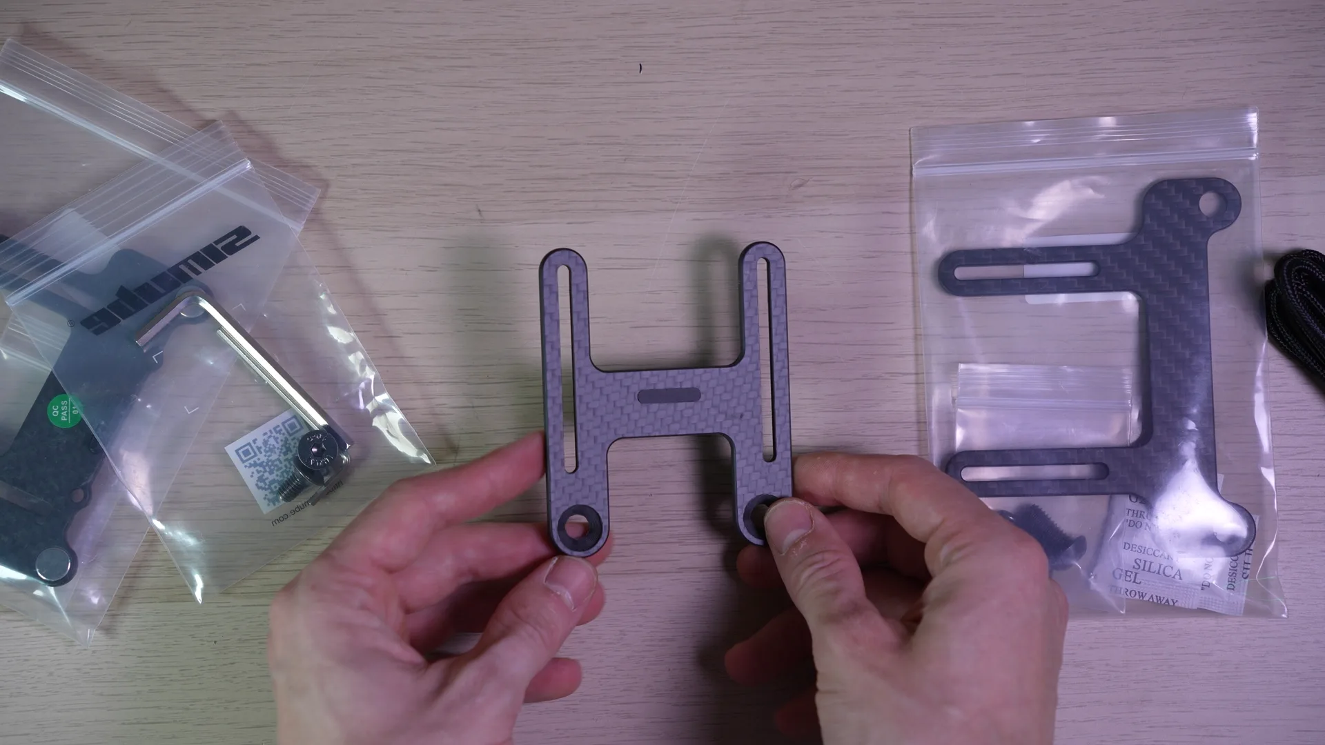 Le support Fanatec en carbone et son patin central, à côté d'autres supports dans leurs sachets